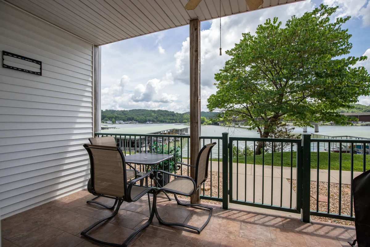 An exterior shot from the condo’s patio area, featuring comfortable outdoor seating with a beautiful lake view framed by a tree. The space looks ideal for family meals, relaxing, or watching wildlife, merging the comfort of home with the outdoor experience.