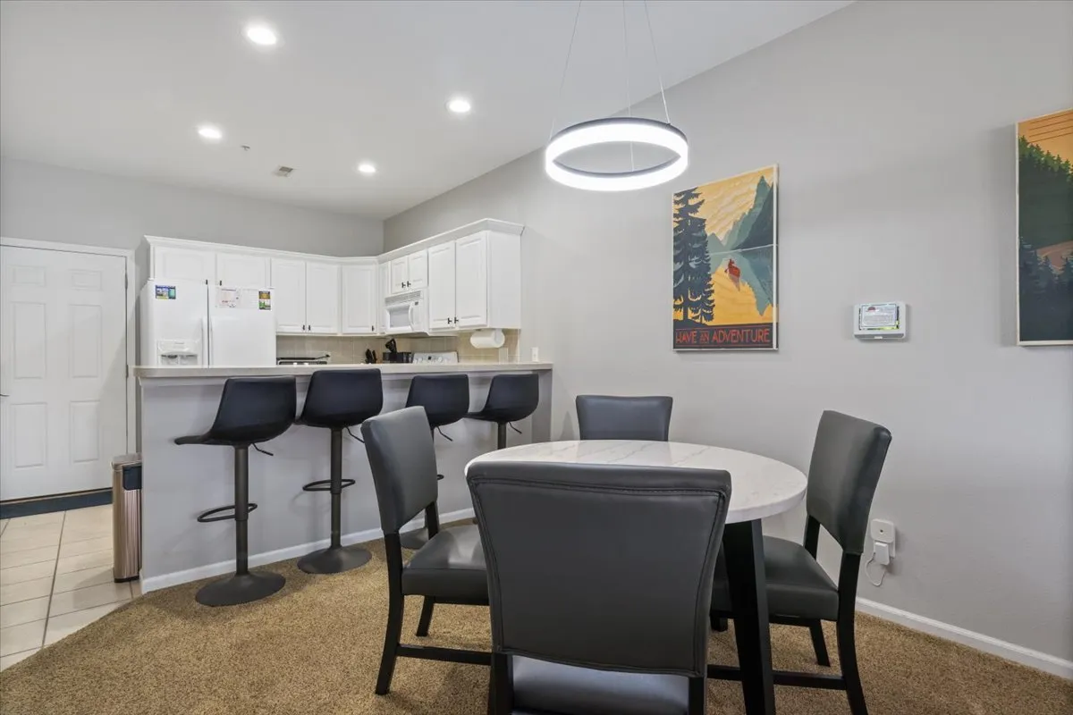 A welcoming view of the dining area and kitchen bar, with a stylish dining table, comfortable seating, and vibrant artwork. The space feels modern and lively, ready for group meals or game nights.