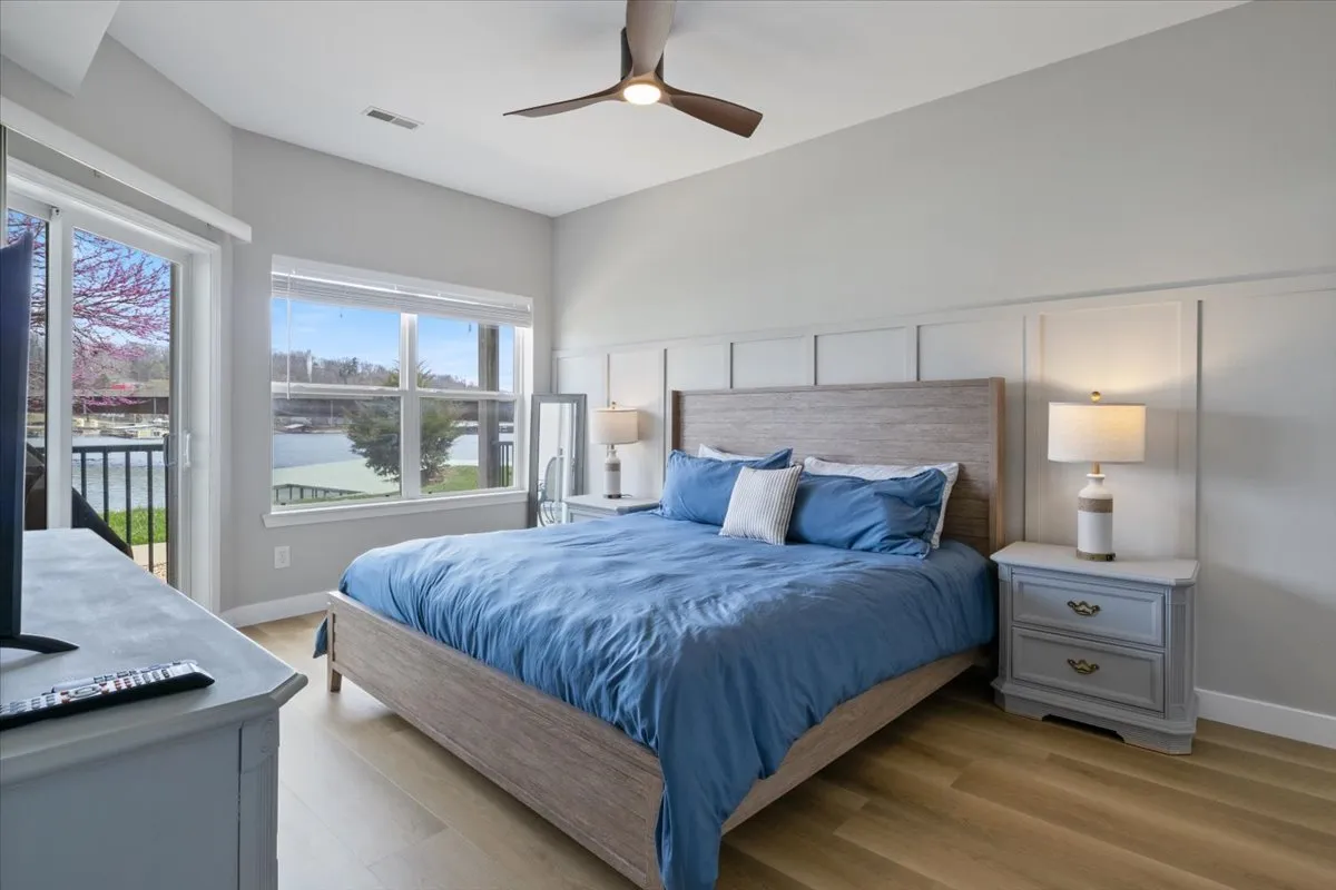 A bright, airy bedroom with a cozy bed, framed by windows offering expansive views of the outdoors. Nightstands and modern light fixtures add comfort and practicality, while the natural light creates an inviting retreat.