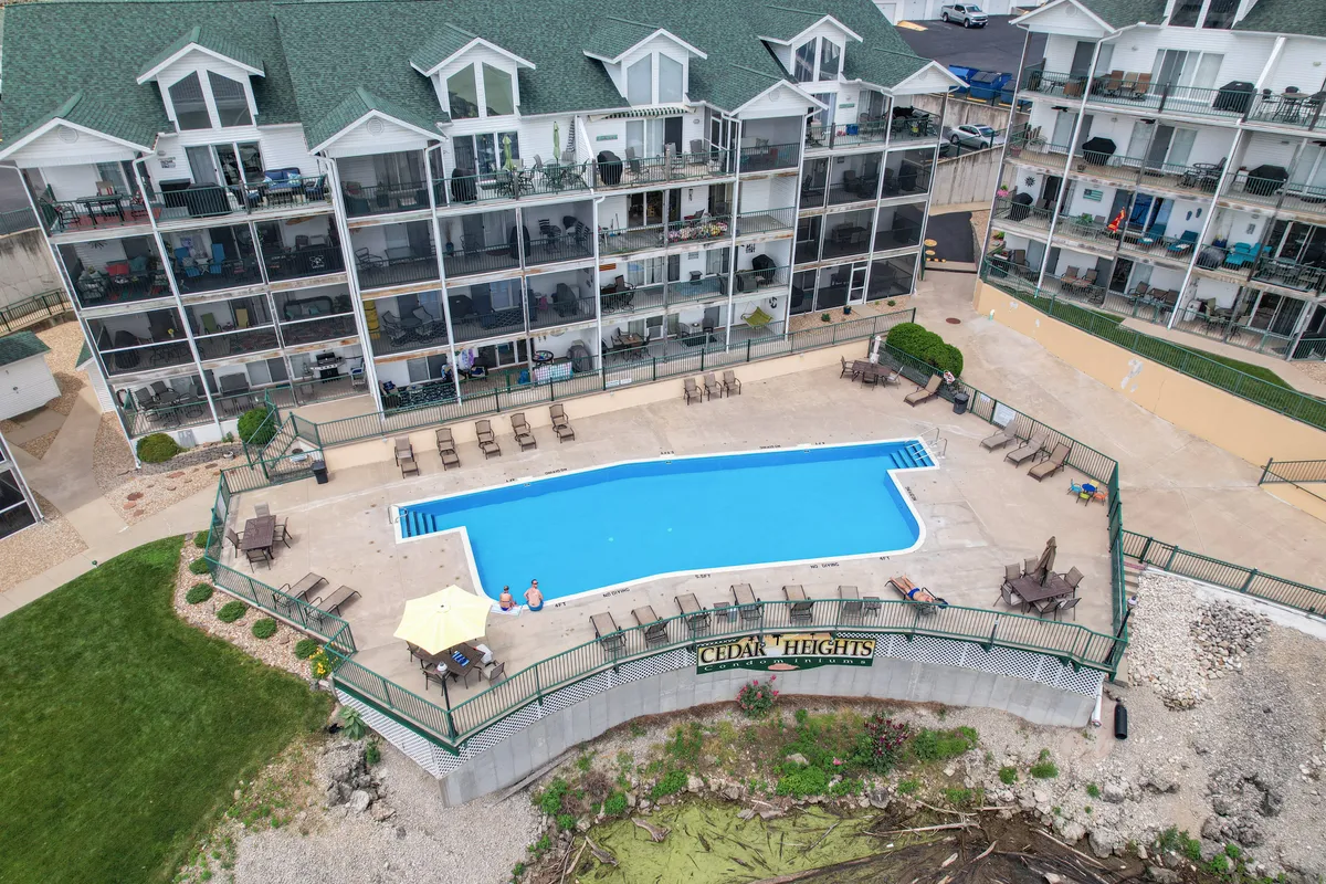 This exterior shot showcases a sparkling community swimming pool with ample seating areas and the condo building facade in the background. The scene is bathed in natural light, creating an inviting and leisurely atmosphere ideal for socializing, swimming, and sunbathing.